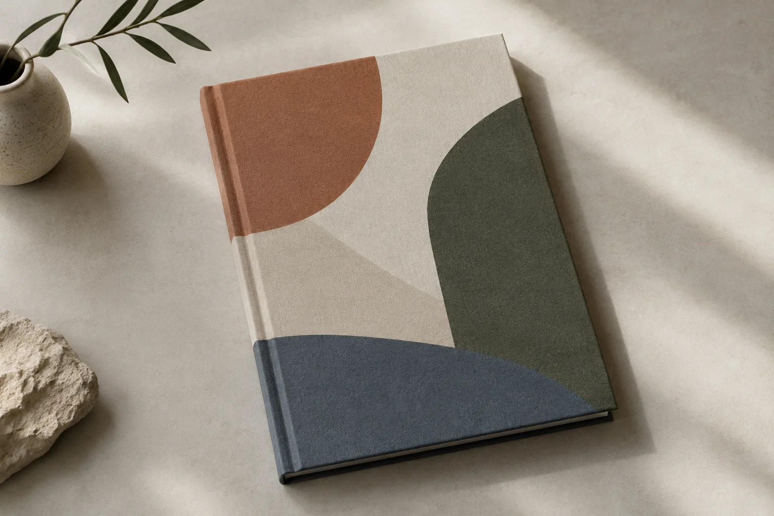 Livre fermé vu en légère plongée, posé sur une surface claire, avec une couverture composée de formes géométriques abstraites.