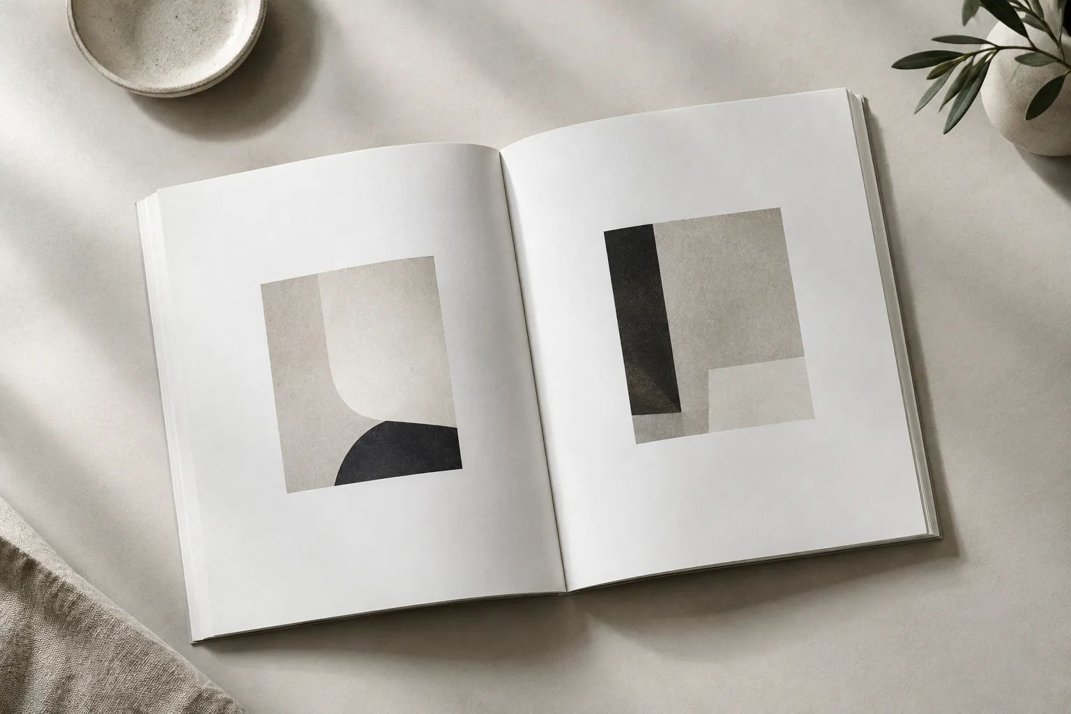 Livre d’art ouvert sur une table claire, avec une petite composition géométrique entourée de larges marges blanches.